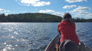 Femme en canot sur le lac Édouard, regardant l’horizon, au SAN – Station boréale