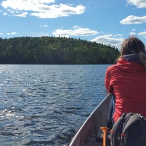 Femme en canot sur le lac Édouard, regardant l’horizon, au SAN – Station boréale